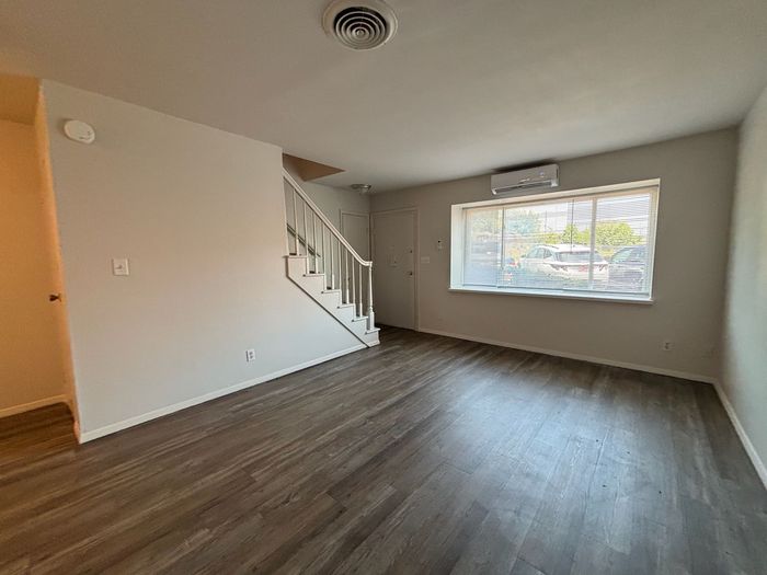 An empty living room with hardwood floors and stairs.
