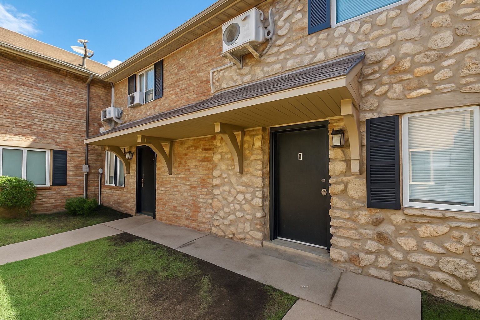 A brick apartment building with a black door and shutters