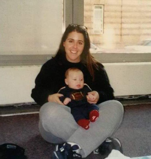 Jennifer Tawil is sitting on the floor holding her baby boy during the first month of postpartum.