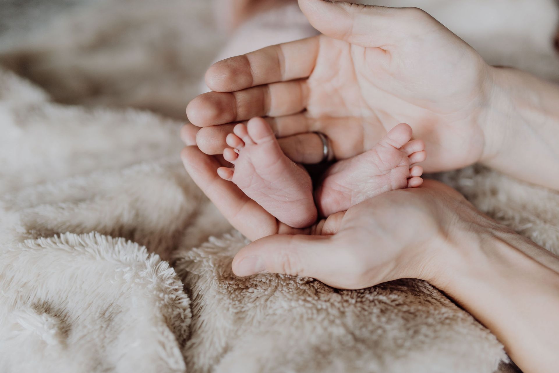 A postpartum mother is holding a baby 's feet in their hands.