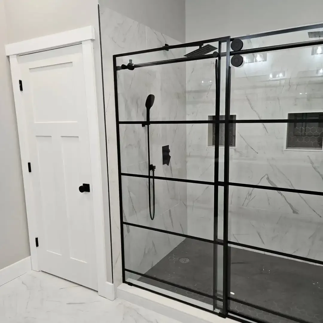 A bathroom with a sliding glass shower door and a white door.