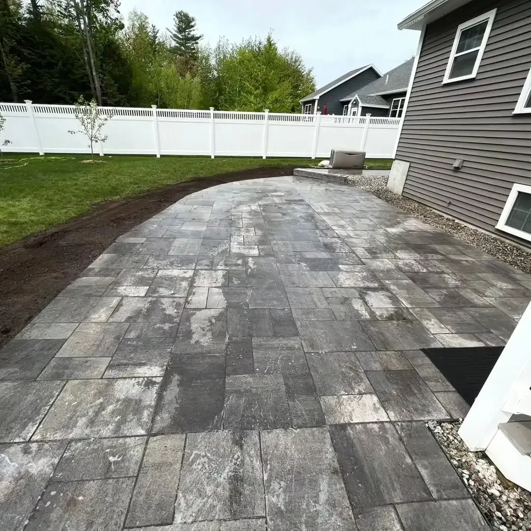 A patio with a white fence and a house in the background.