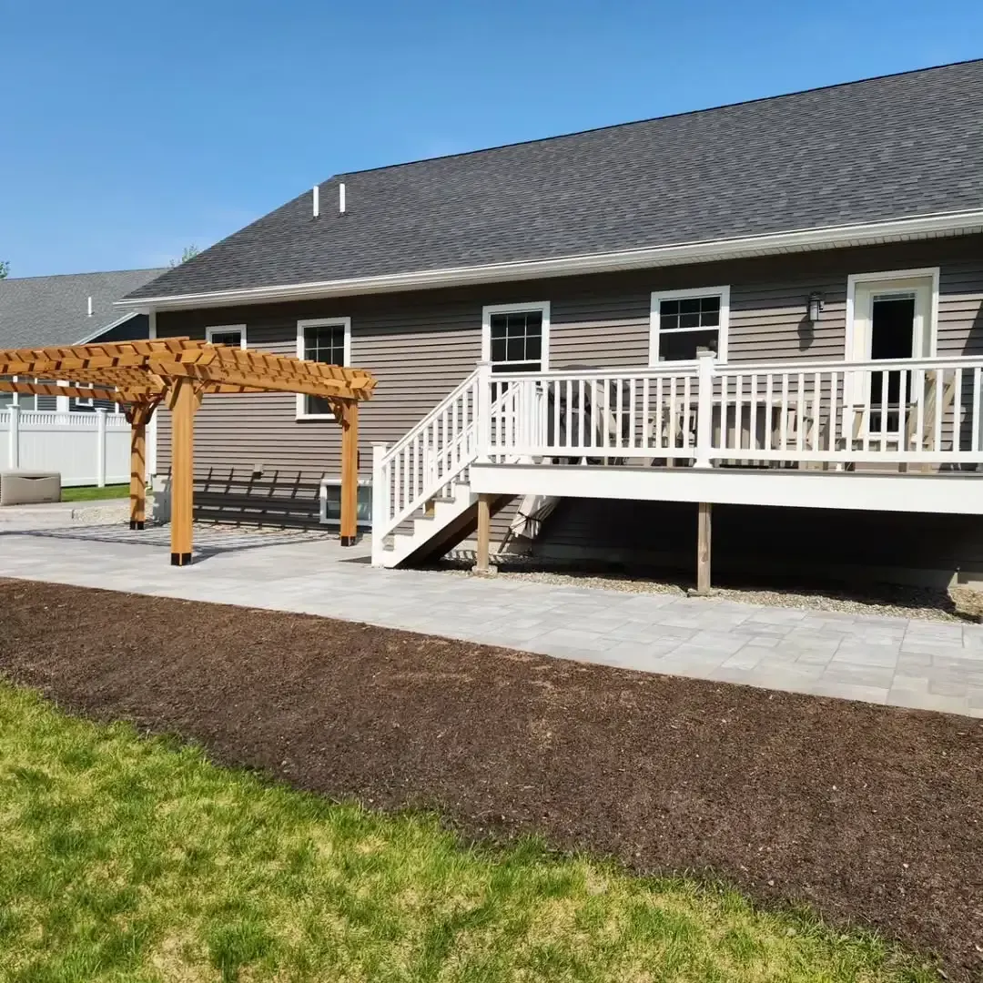 A house with a deck and a pergola in front of it