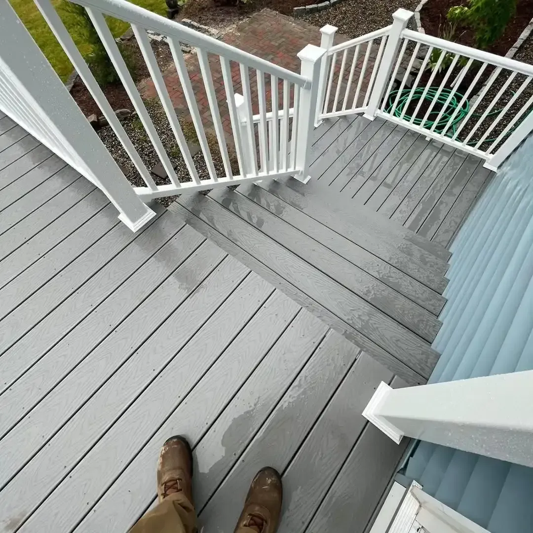 A person is standing on a deck with stairs and a white railing.