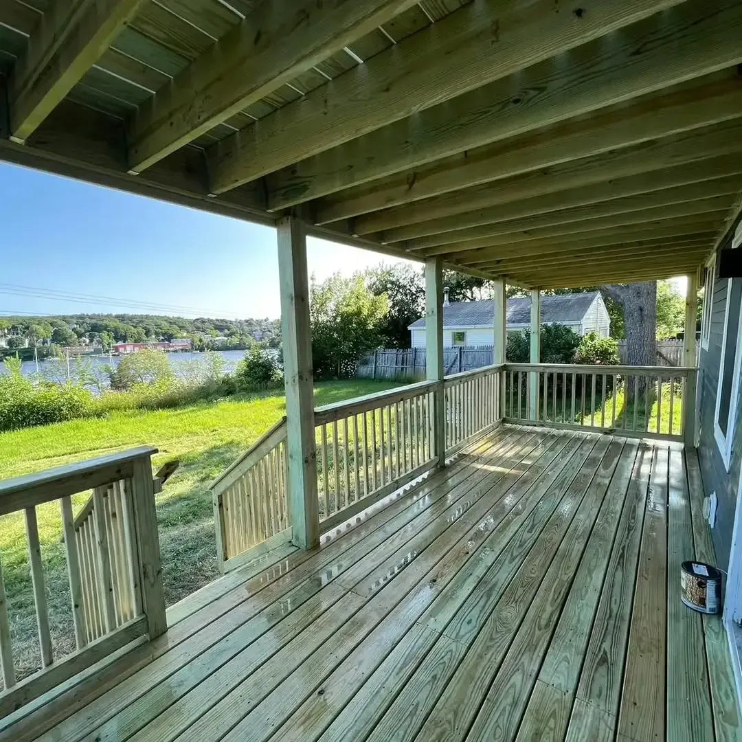A large wooden deck with a view of a lake.