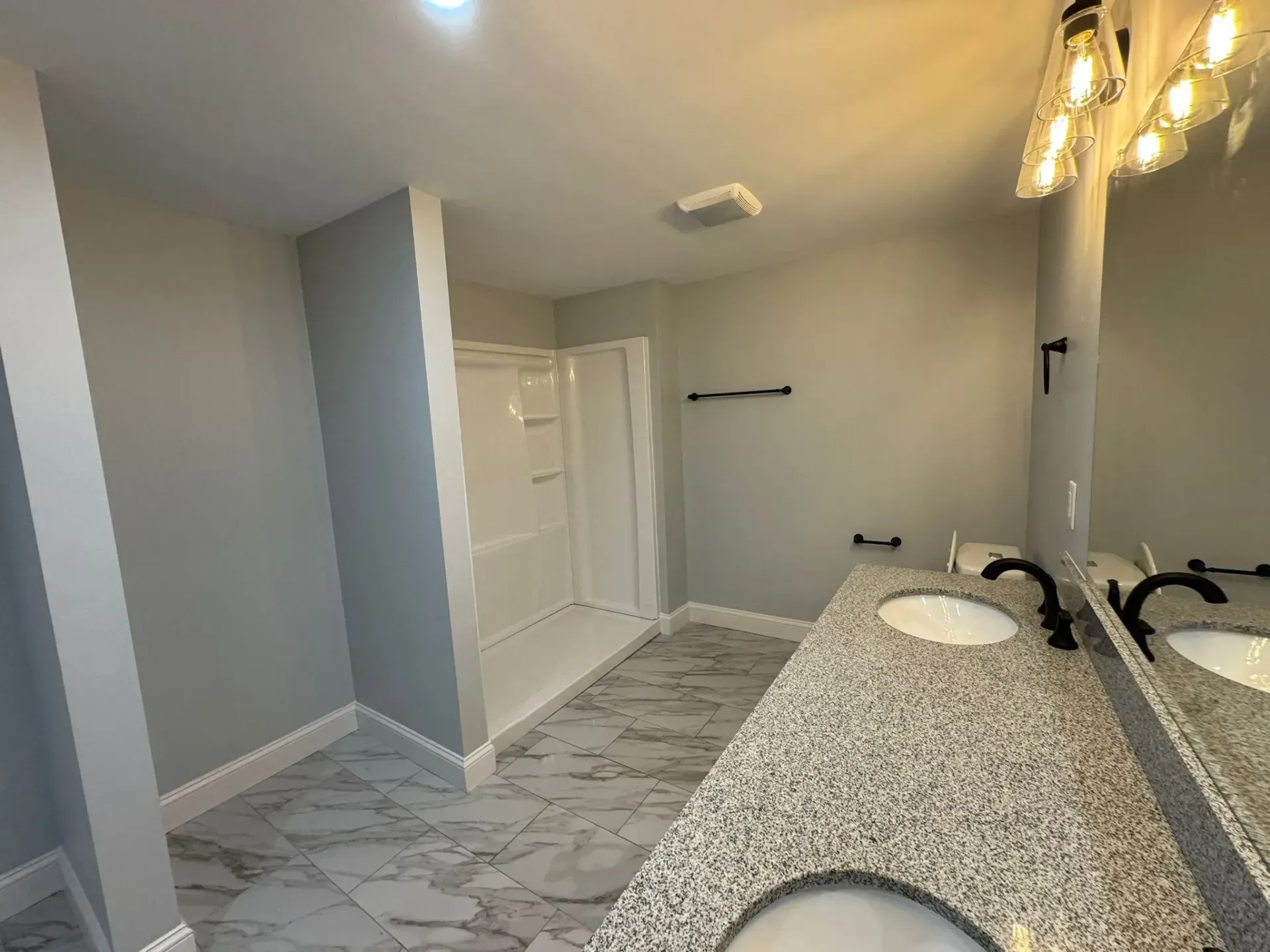 A bathroom with two sinks and a shower.