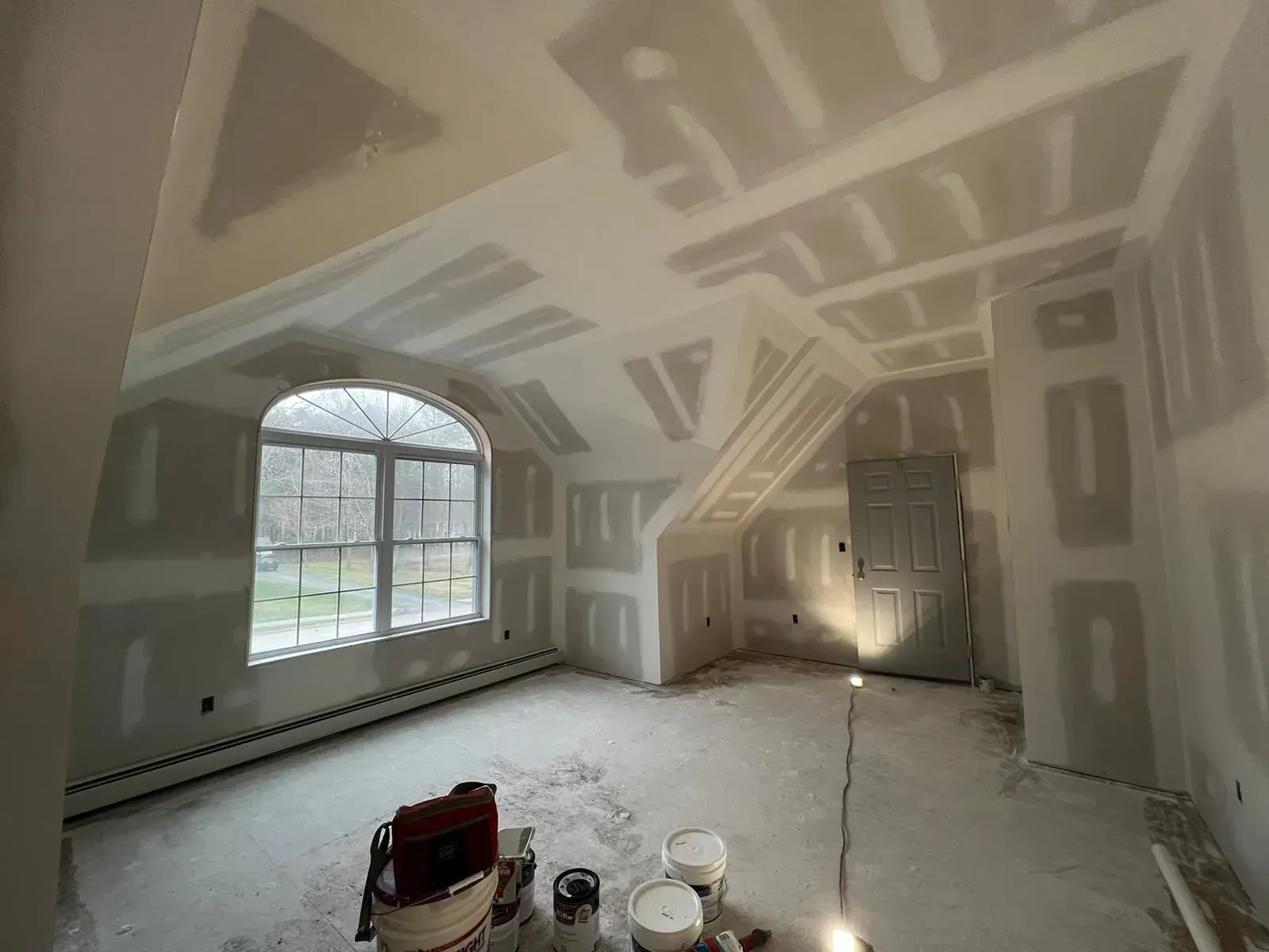 A room with a lot of drywall and a window.