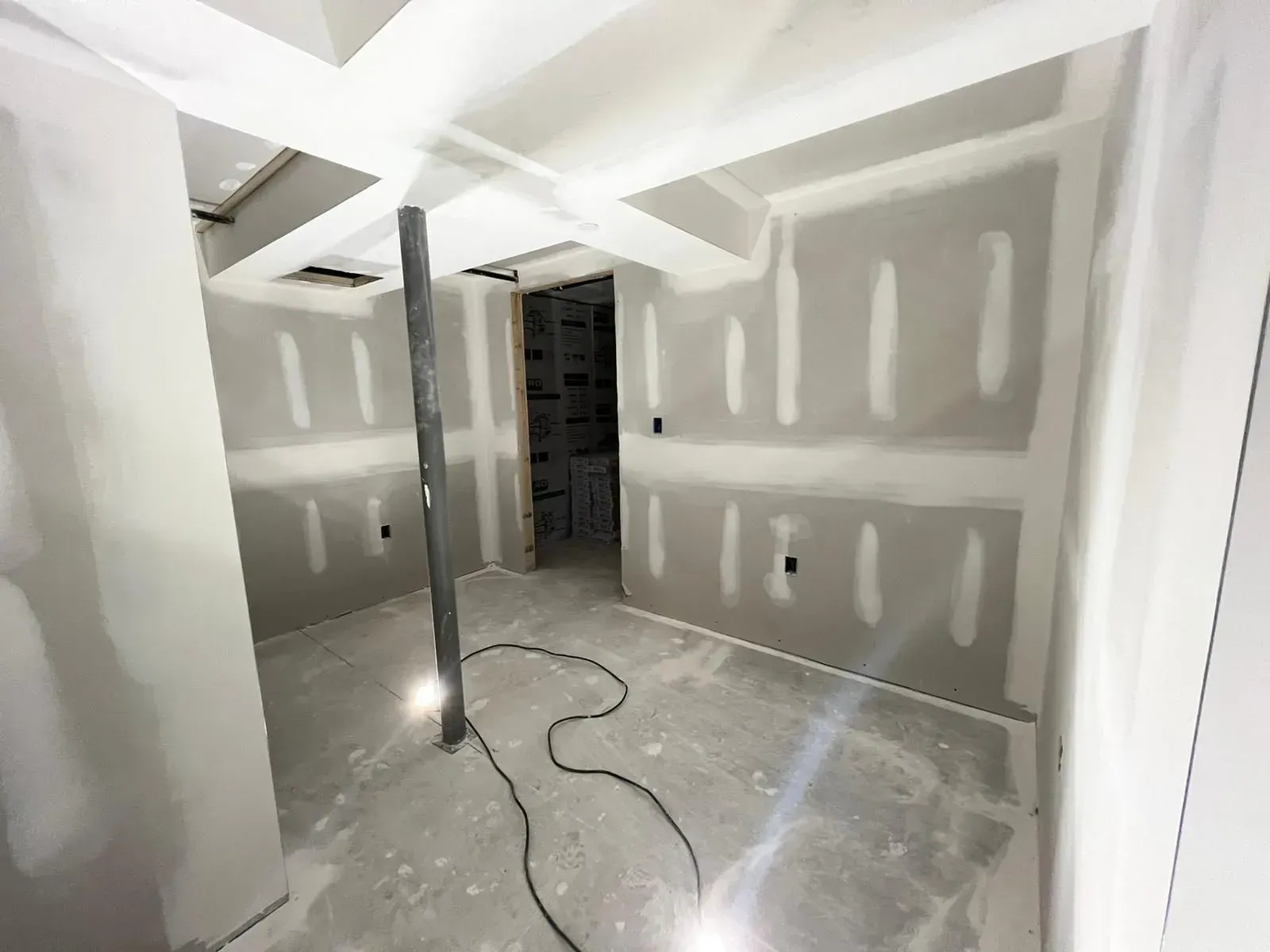 A room with drywall walls and a light on the floor.