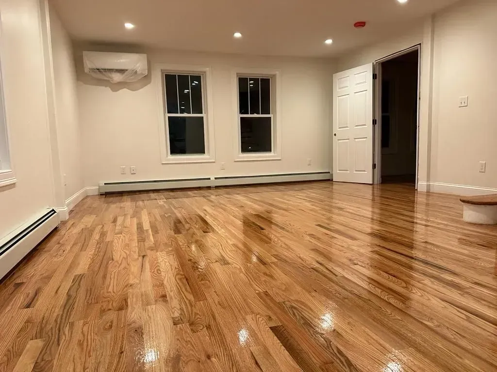 An empty living room with hardwood floors and white walls