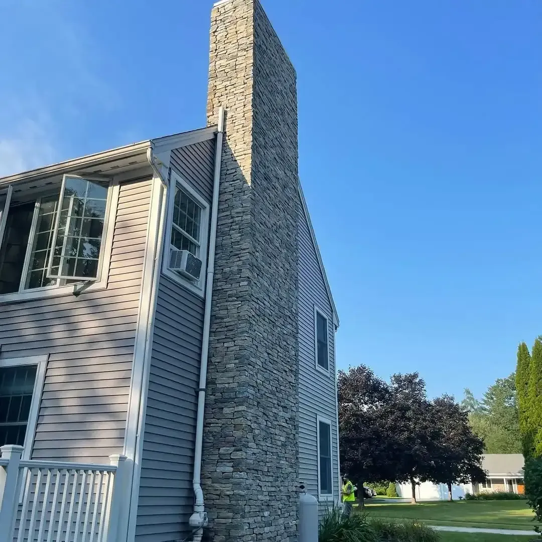 A large house with a chimney on the side of it.