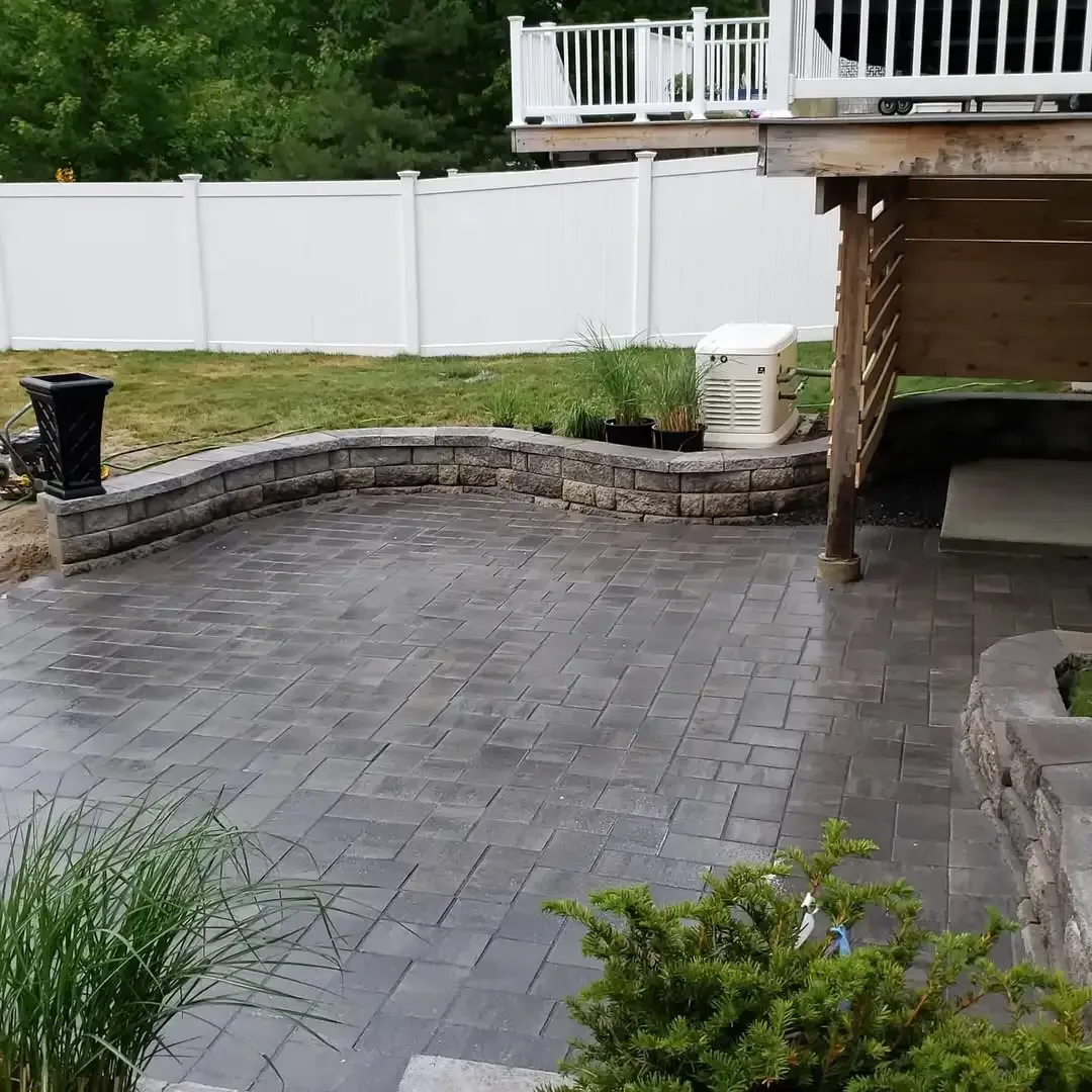 A patio with a deck and a white fence in the background.