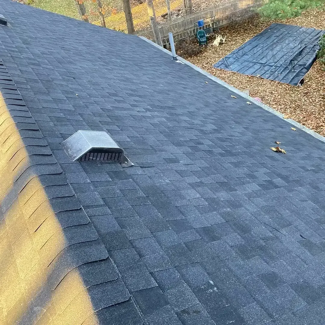 A close up of a black roof with a vent on it.