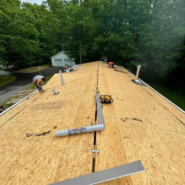 A group of people are working on the roof of a house.