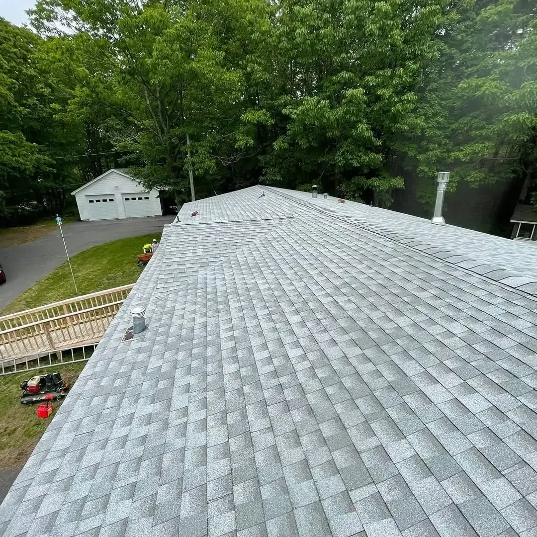 A roof with a lot of shingles on it is surrounded by trees.