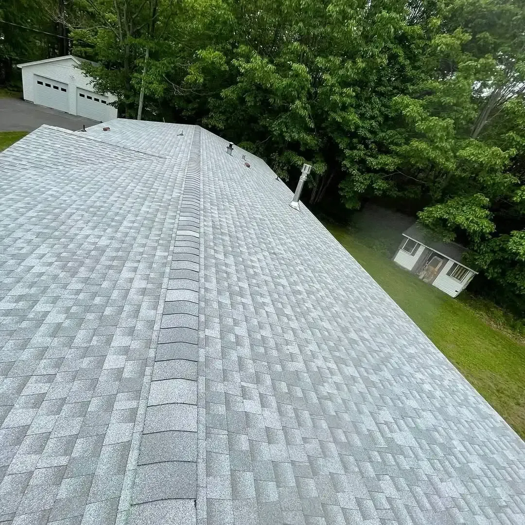 An aerial view of a roof with a lot of shingles and trees in the background.