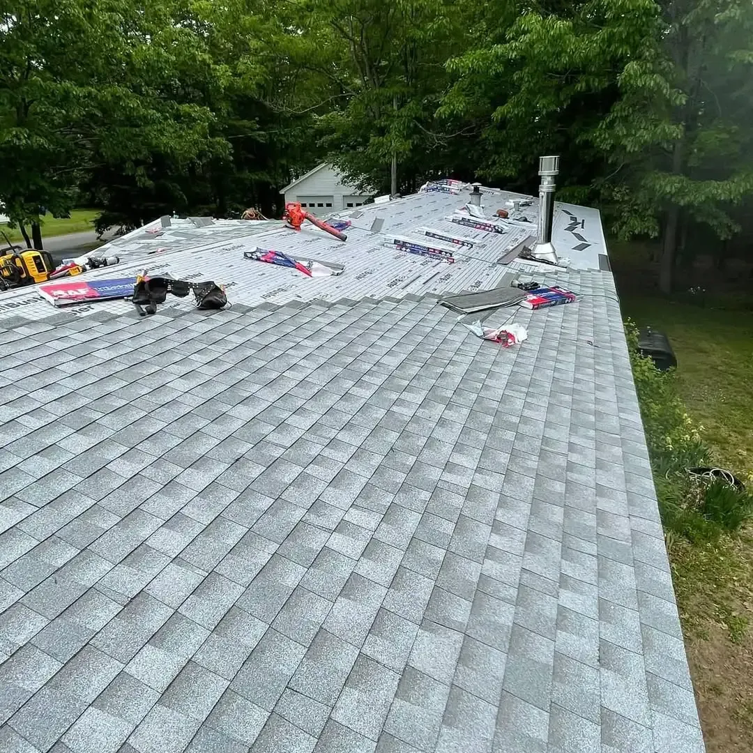 A roof with a lot of shingles on it is being installed on a house.