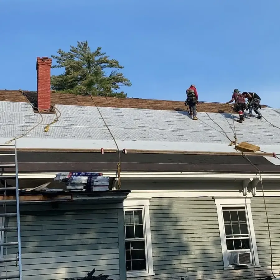 A group of people are working on the roof of a house.