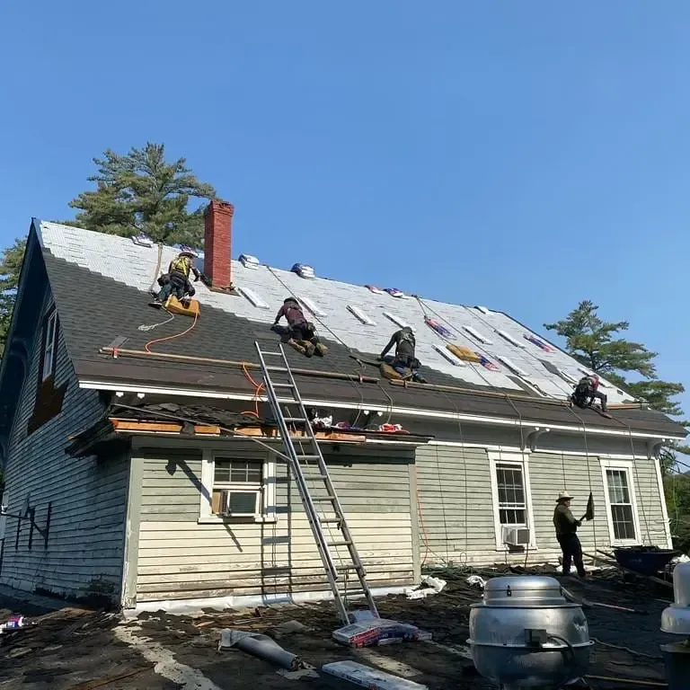 A group of people are working on the roof of a house.