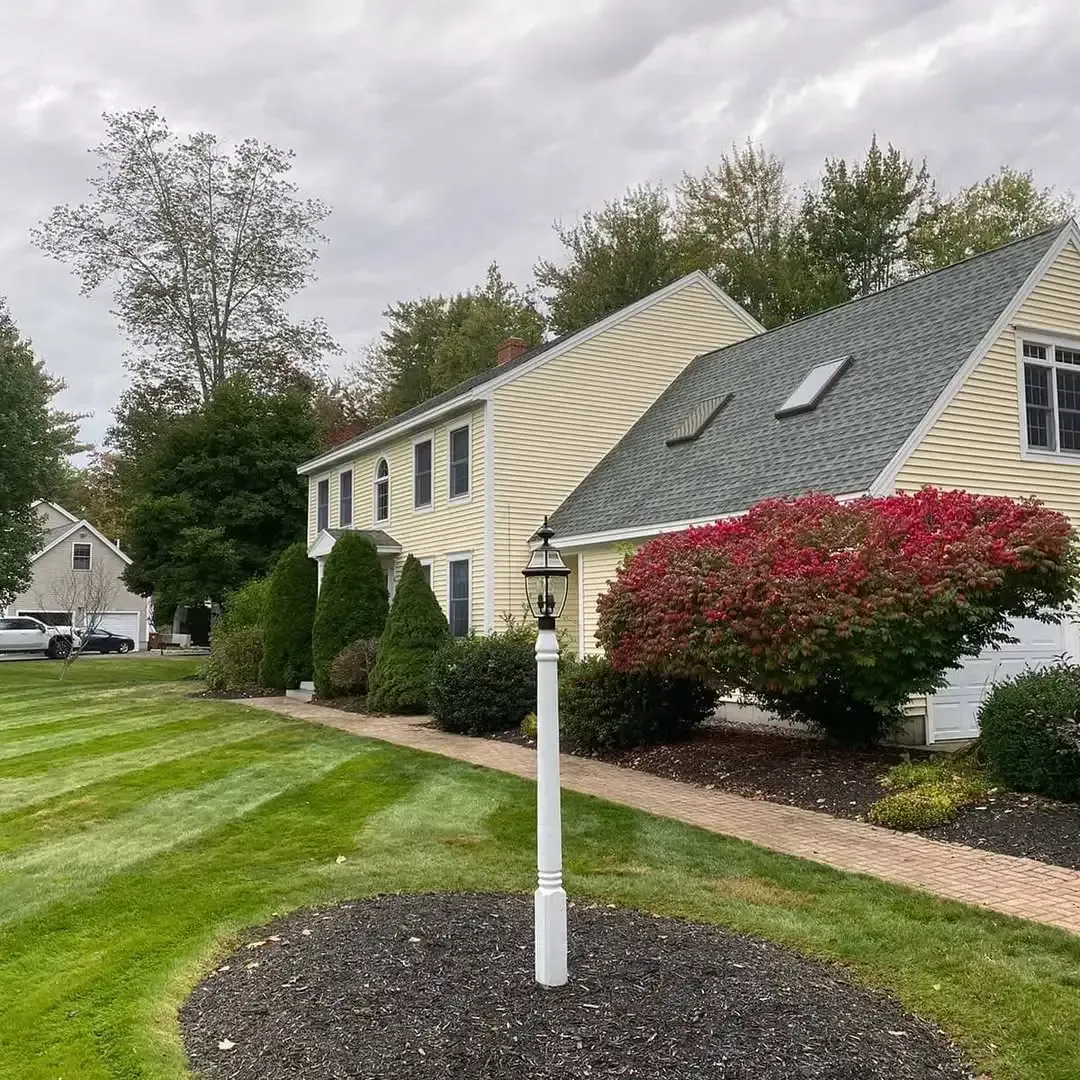 A house with a green lawn and a white pole in front of it