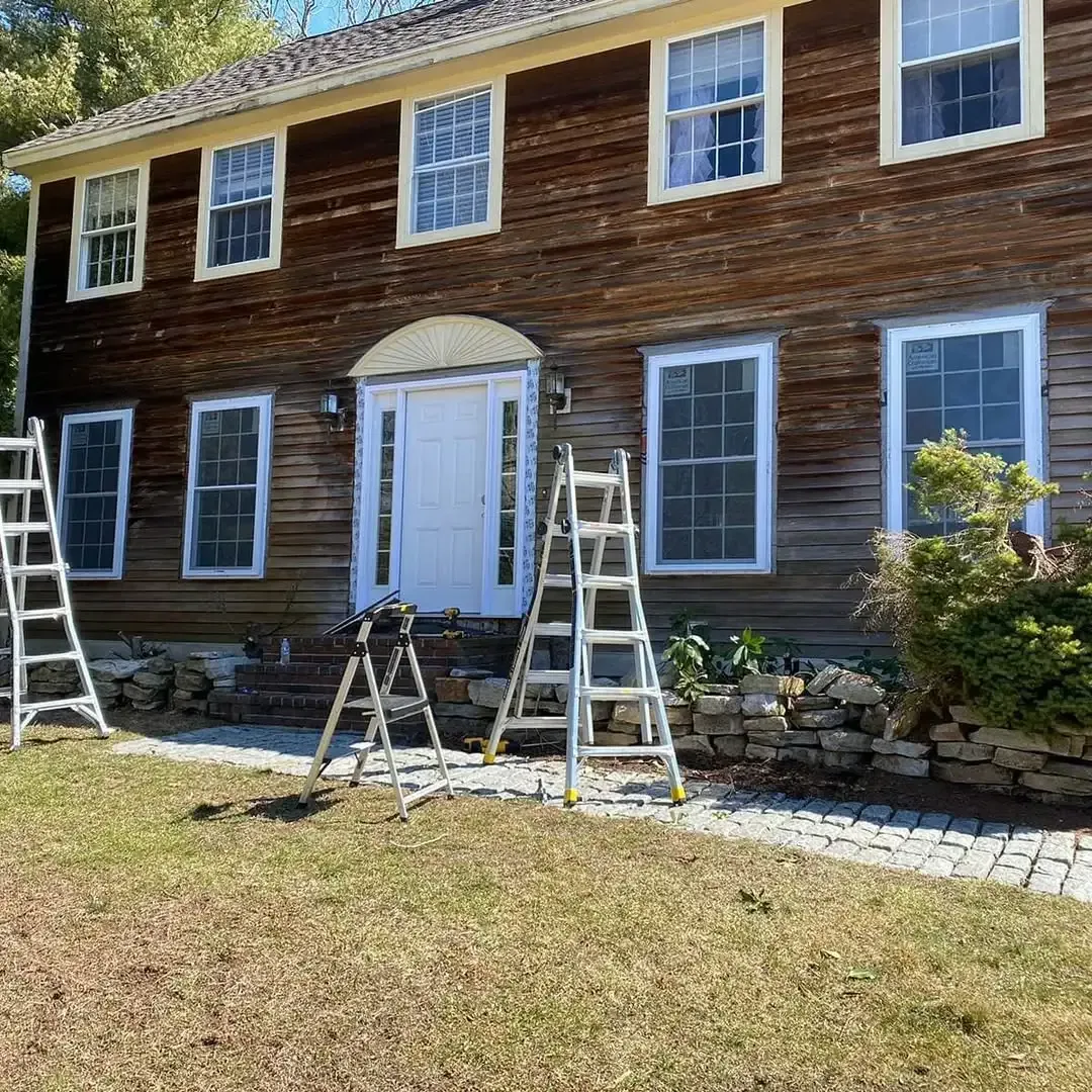 Two ladders are sitting in front of a large wooden house.