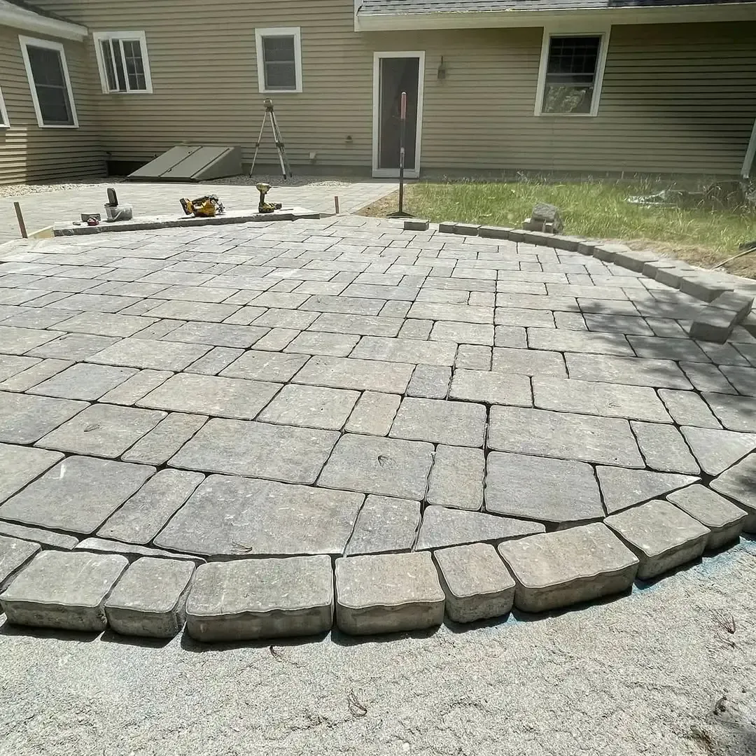 A circular brick patio in front of a house.
