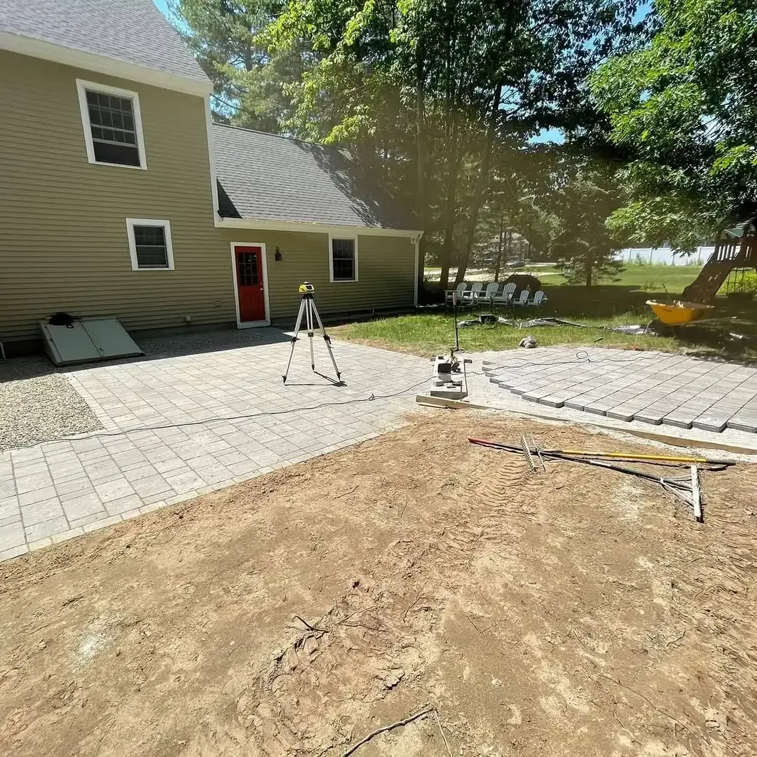 A man is standing on a tripod in front of a house.