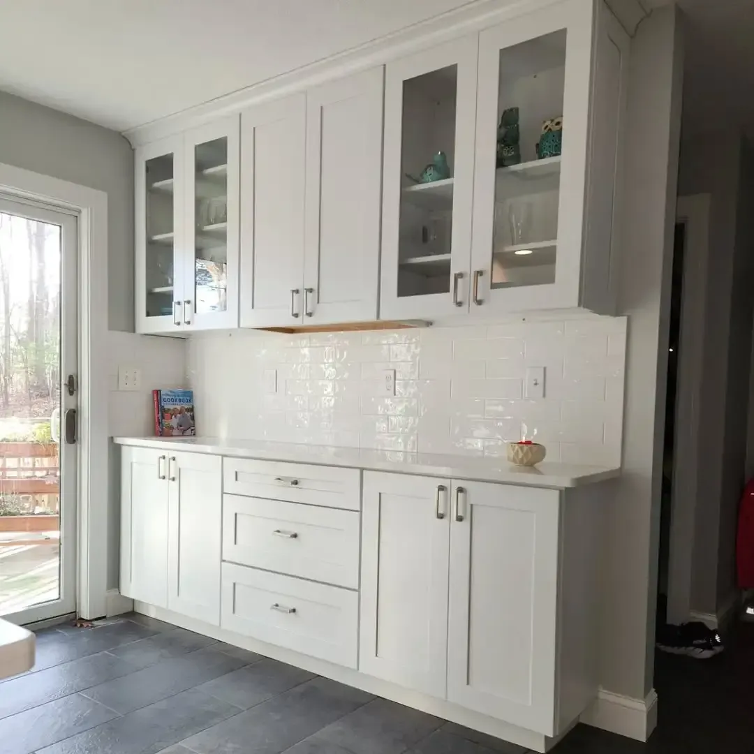 A kitchen with white cabinets and a sliding glass door