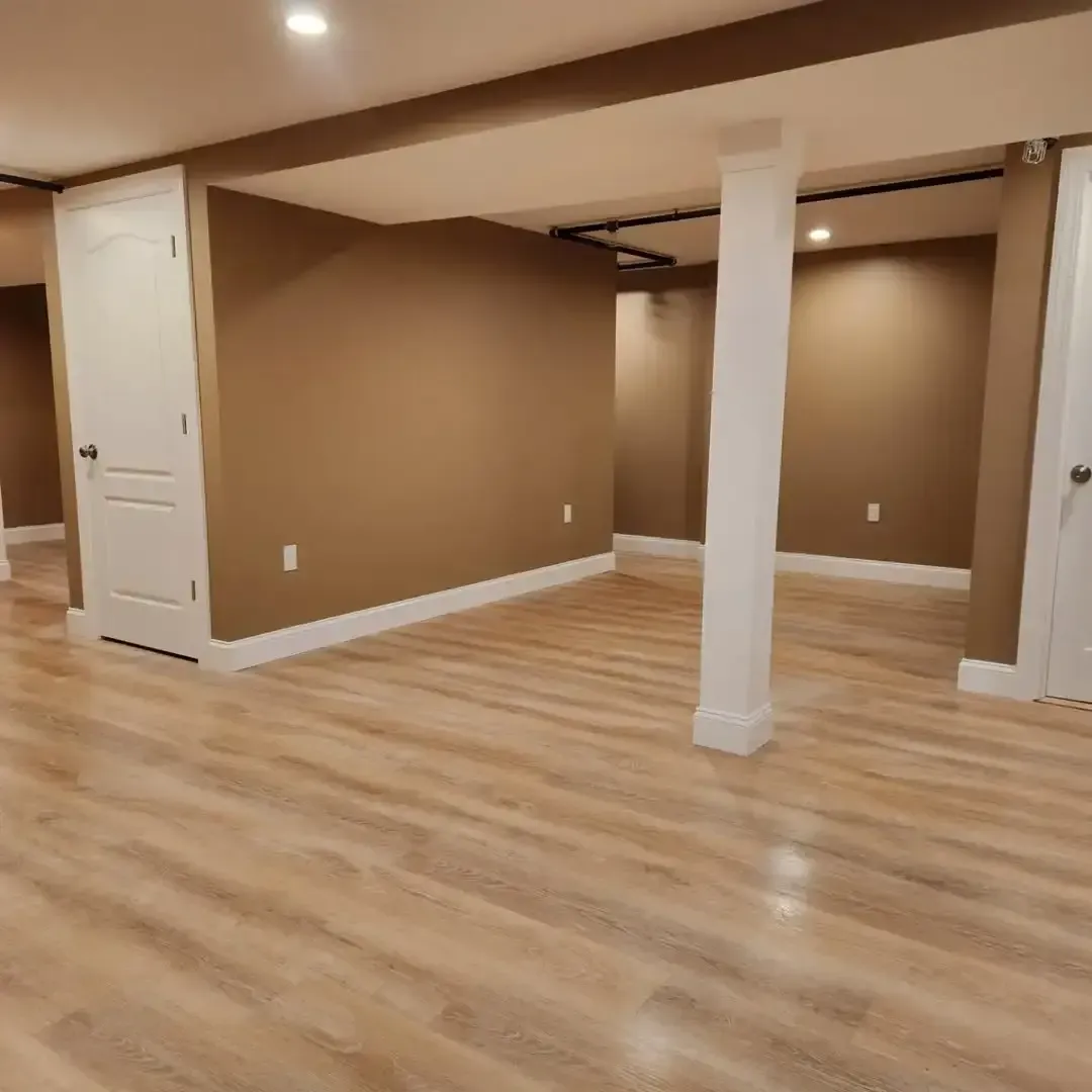 An empty basement with hardwood floors and brown walls.