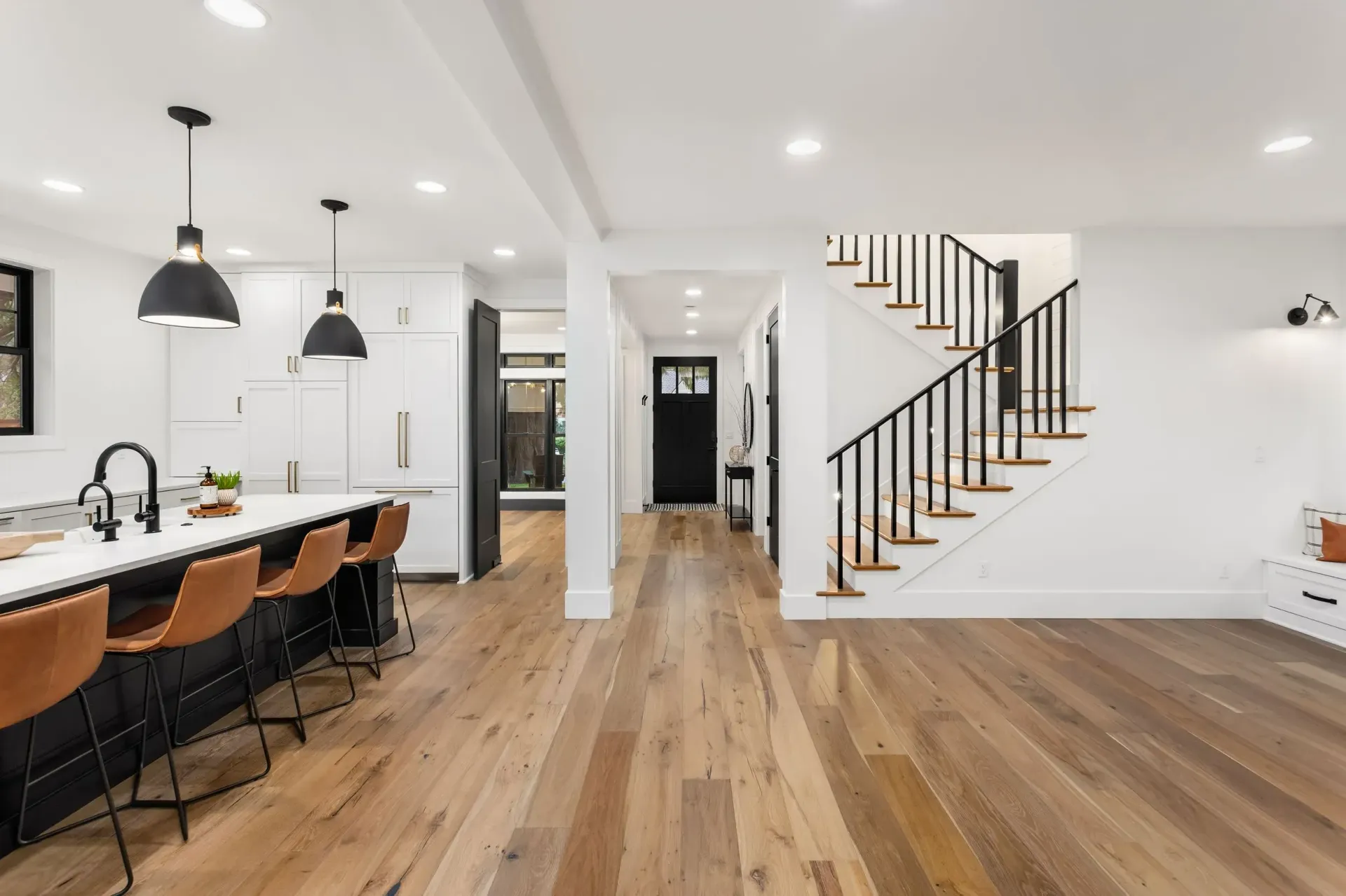 A kitchen with a wooden floor and stairs in a house.