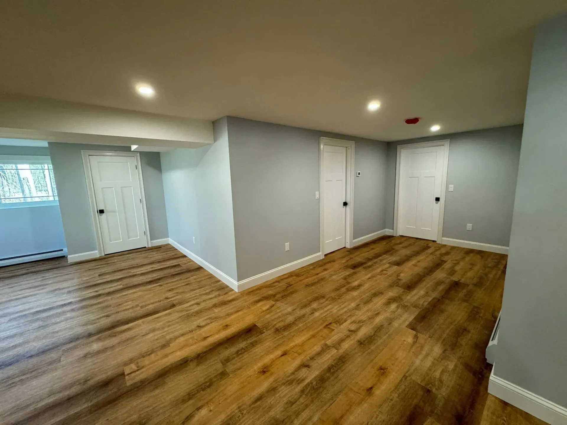 A large empty room with hardwood floors and gray walls.