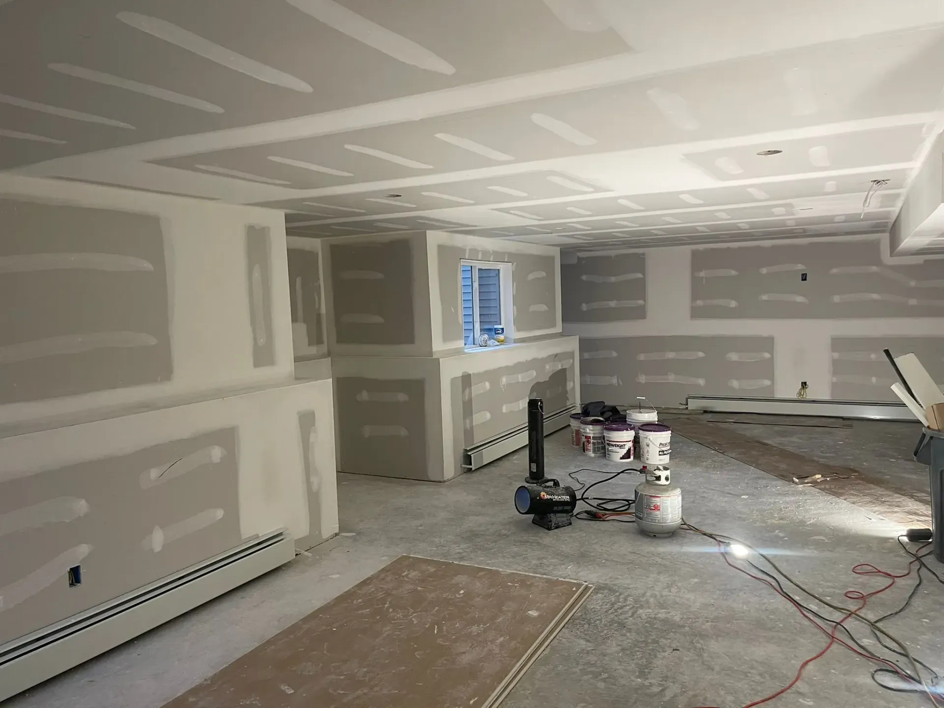 A man is standing in a room with a lot of drywall on the walls.
