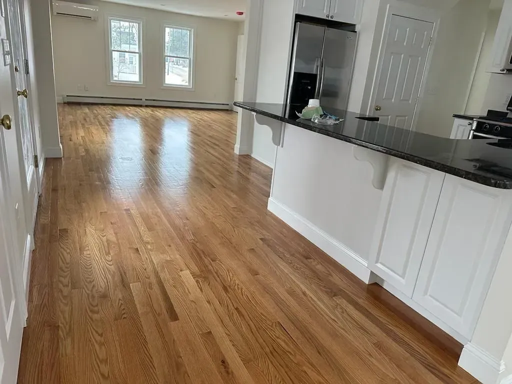 A kitchen with hardwood floors and a stainless steel refrigerator.