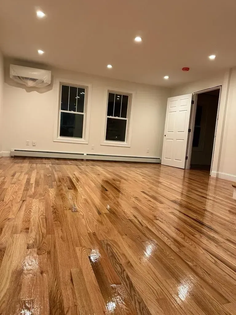 An empty living room with hardwood floors and white walls.