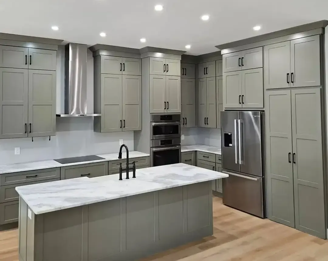 A kitchen with gray cabinets , stainless steel appliances , and a large island.