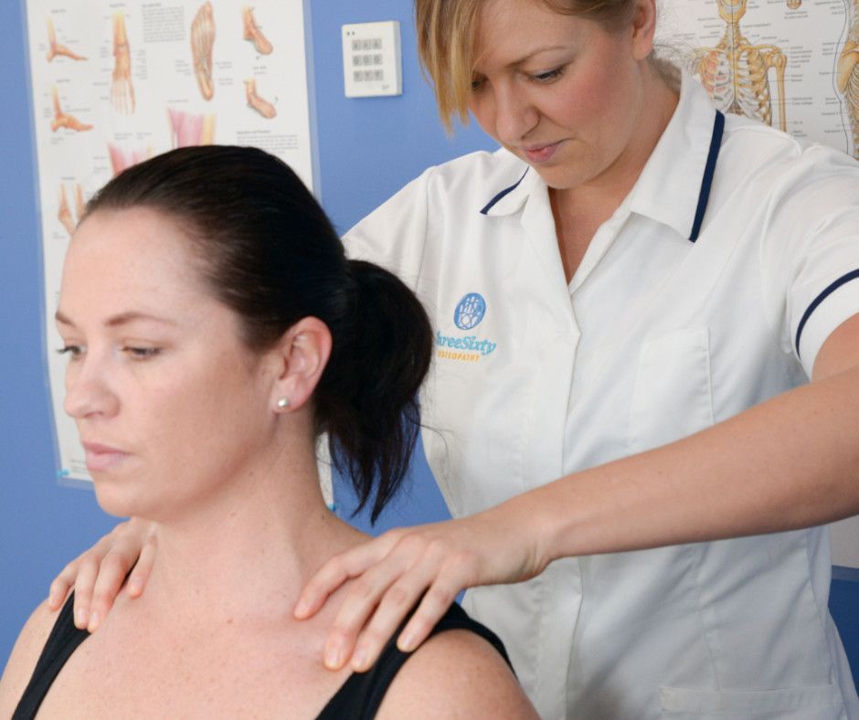 Woman receiving shoulder massage from a healthcare professional; clinic setting.