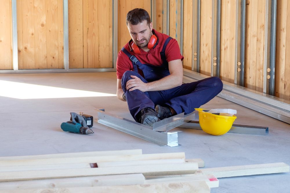 Construction worker injured on the job, clutching his knee.