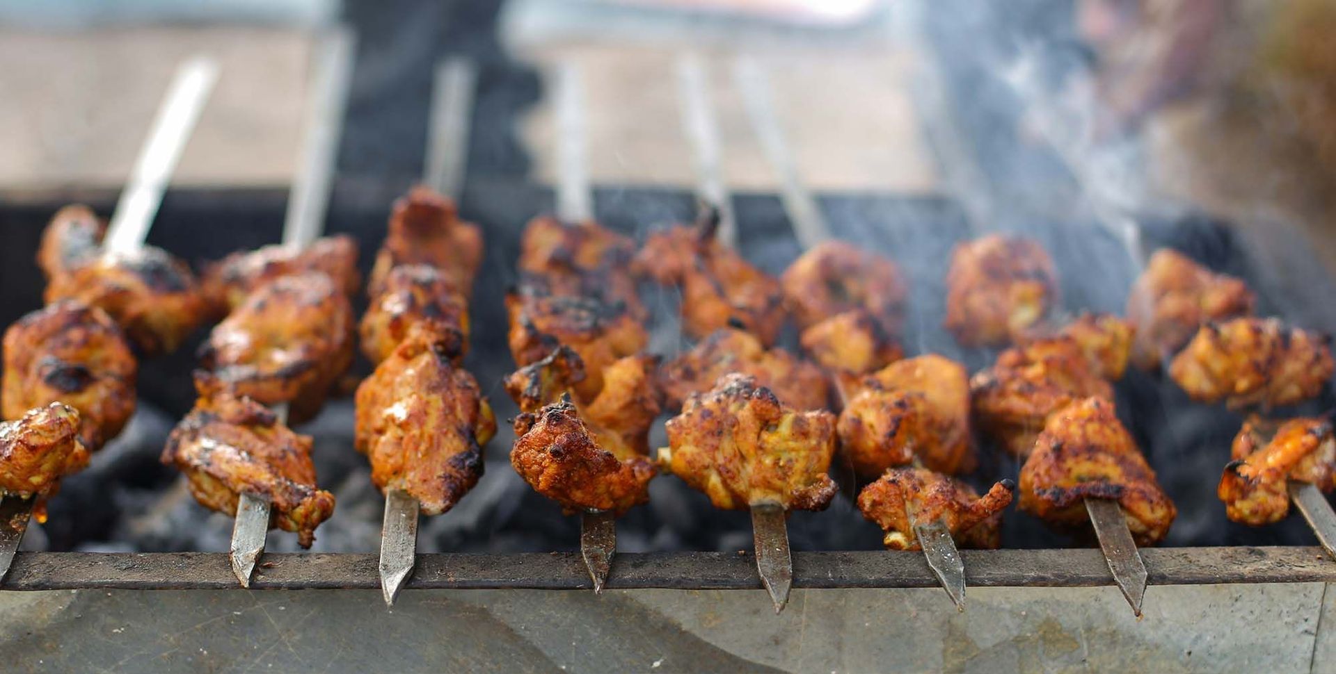 Grilled skewered chicken wings sizzling over charcoal on a barbecue grill