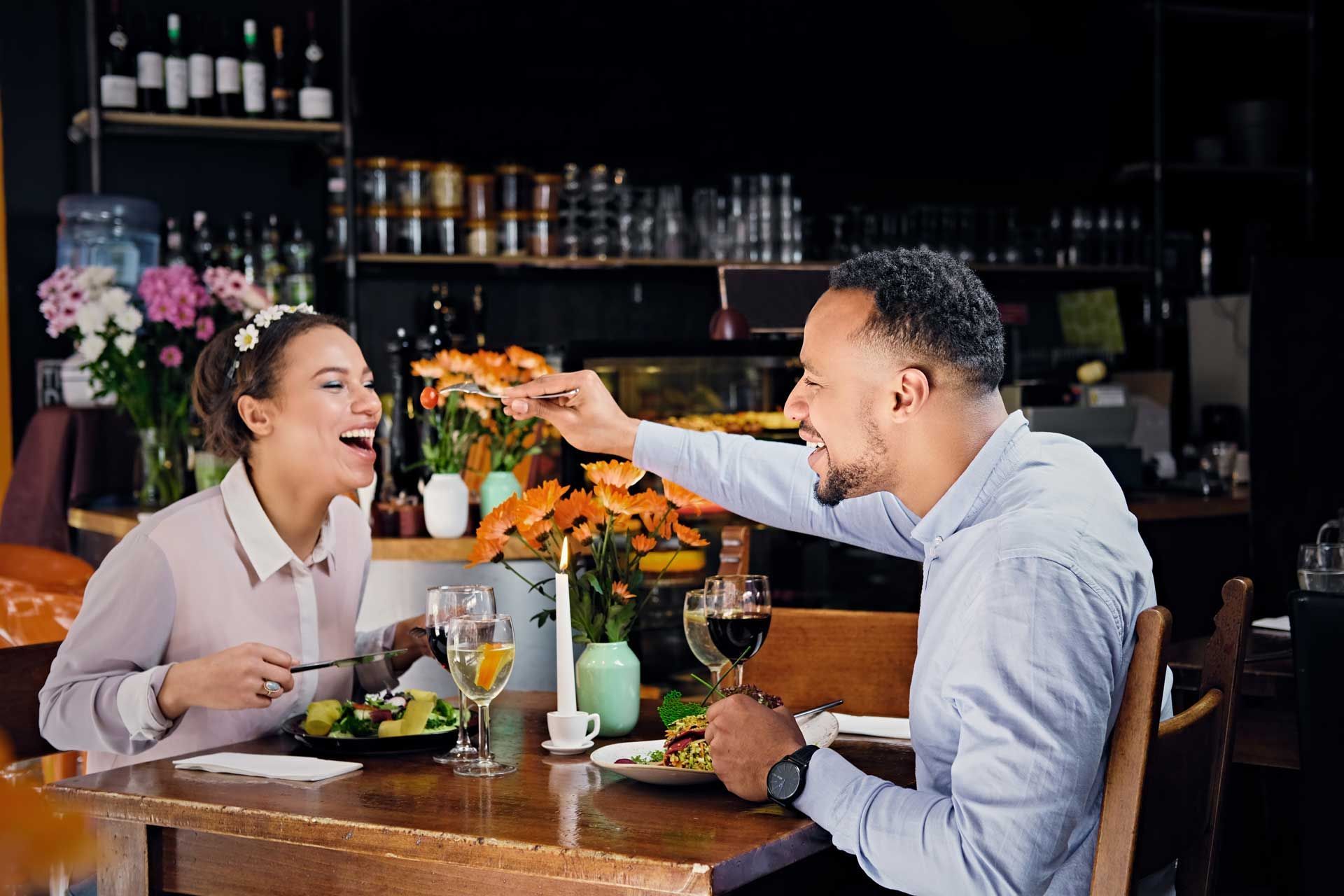 A man and a woman are sitting at a table in a restaurant eating food.