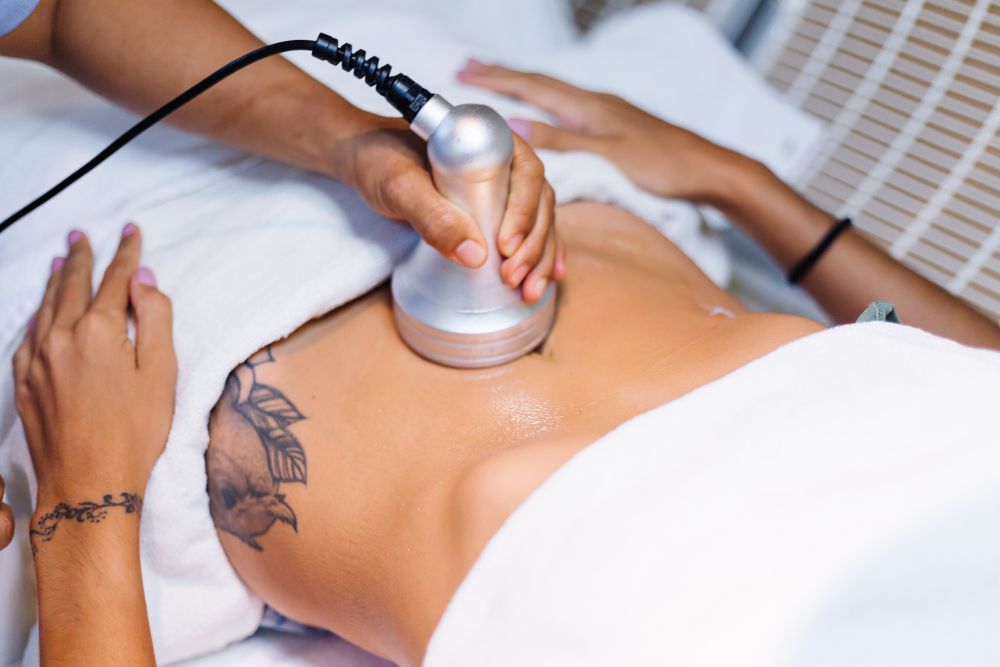 A person receiving body treatment with a handheld device on their torso.