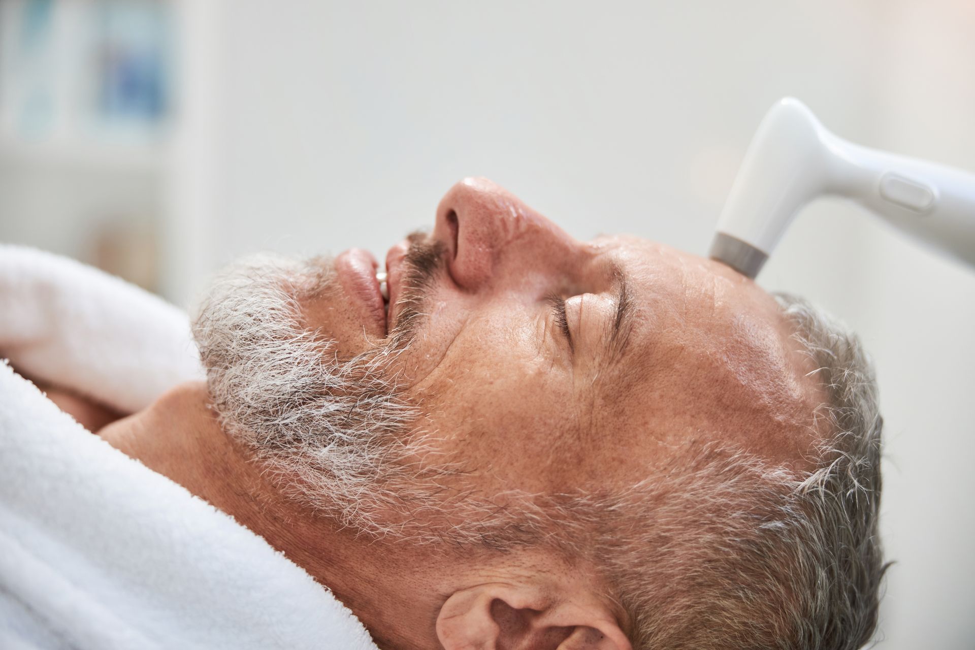 A man with a beard is getting a facial treatment at a spa.