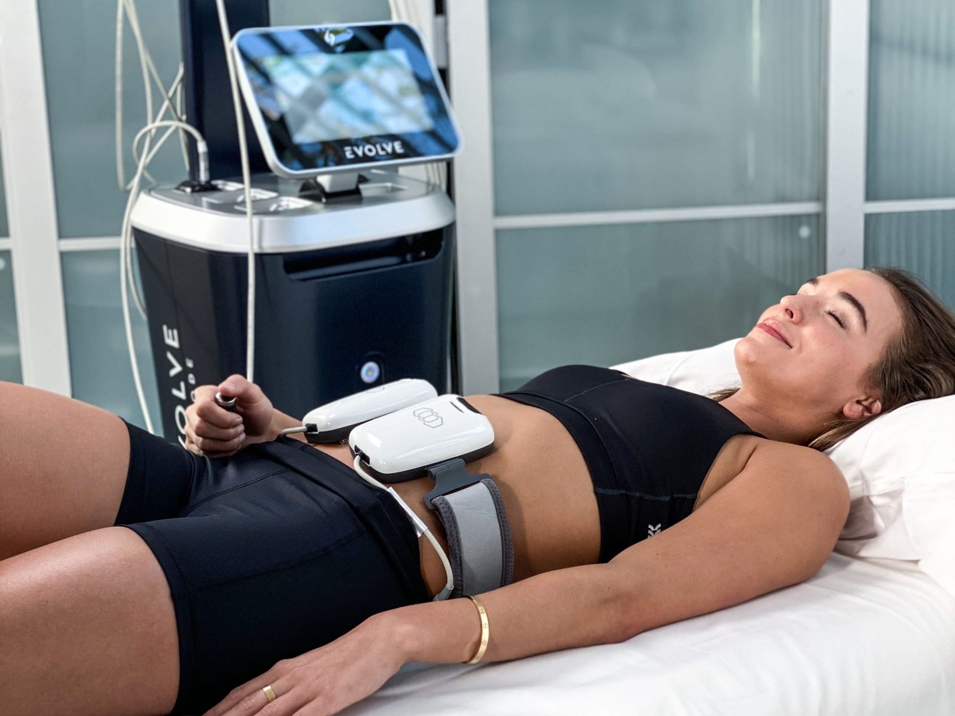 a woman is laying on a bed with a machine on her stomach .