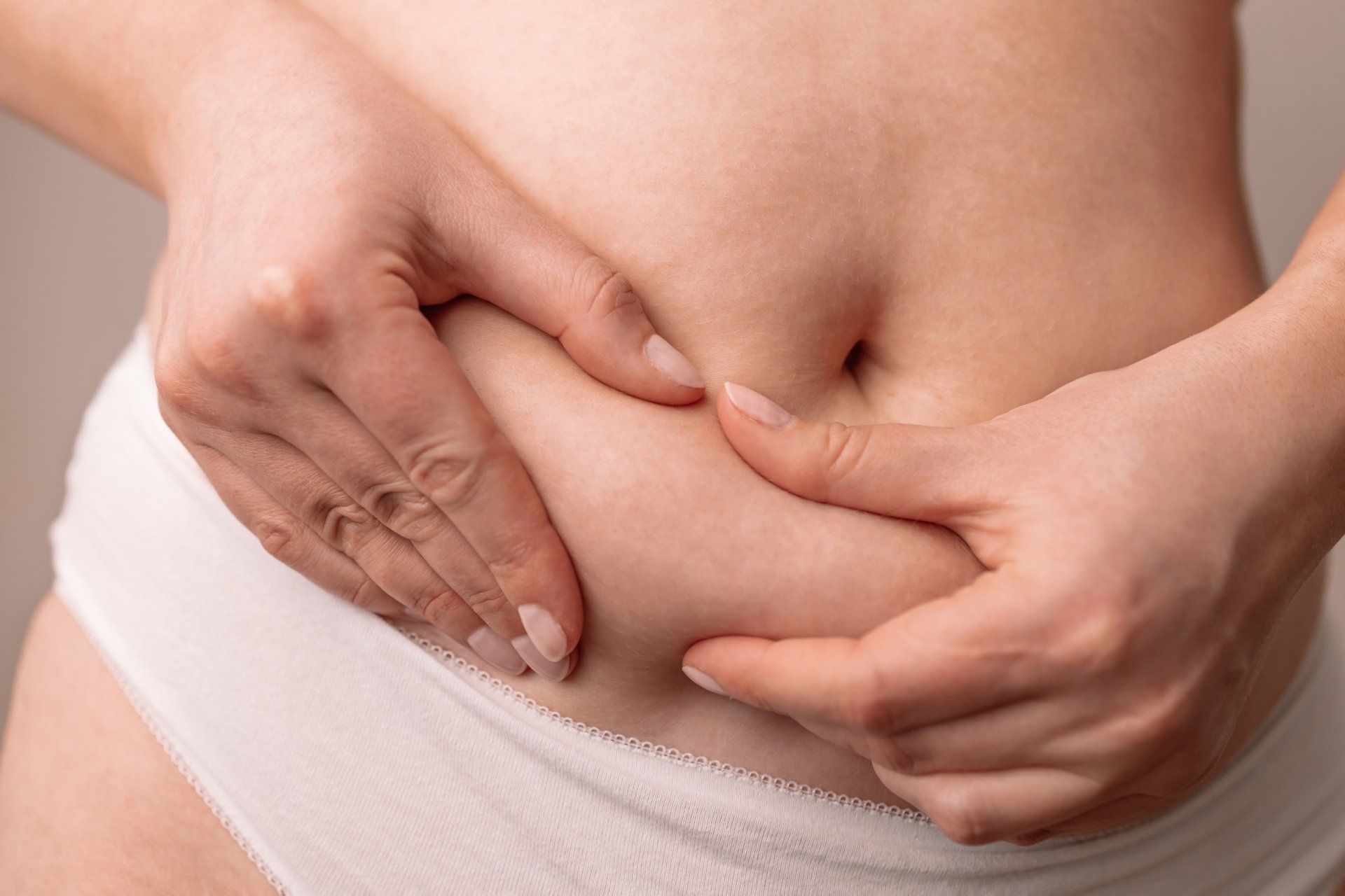 a woman is holding her stomach with her hands .