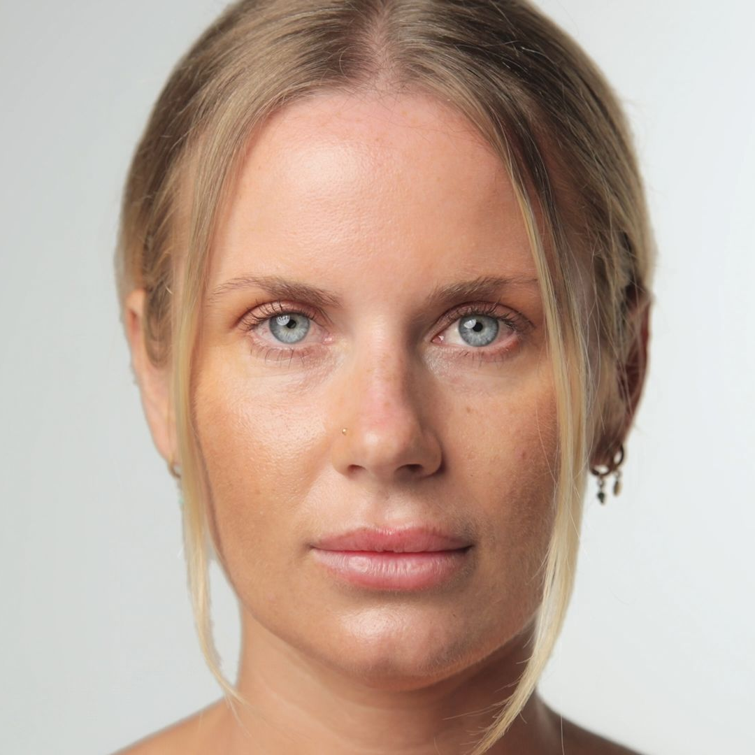 Woman with light blonde hair and blue eyes, looking at the camera. Neutral expression, studio background.