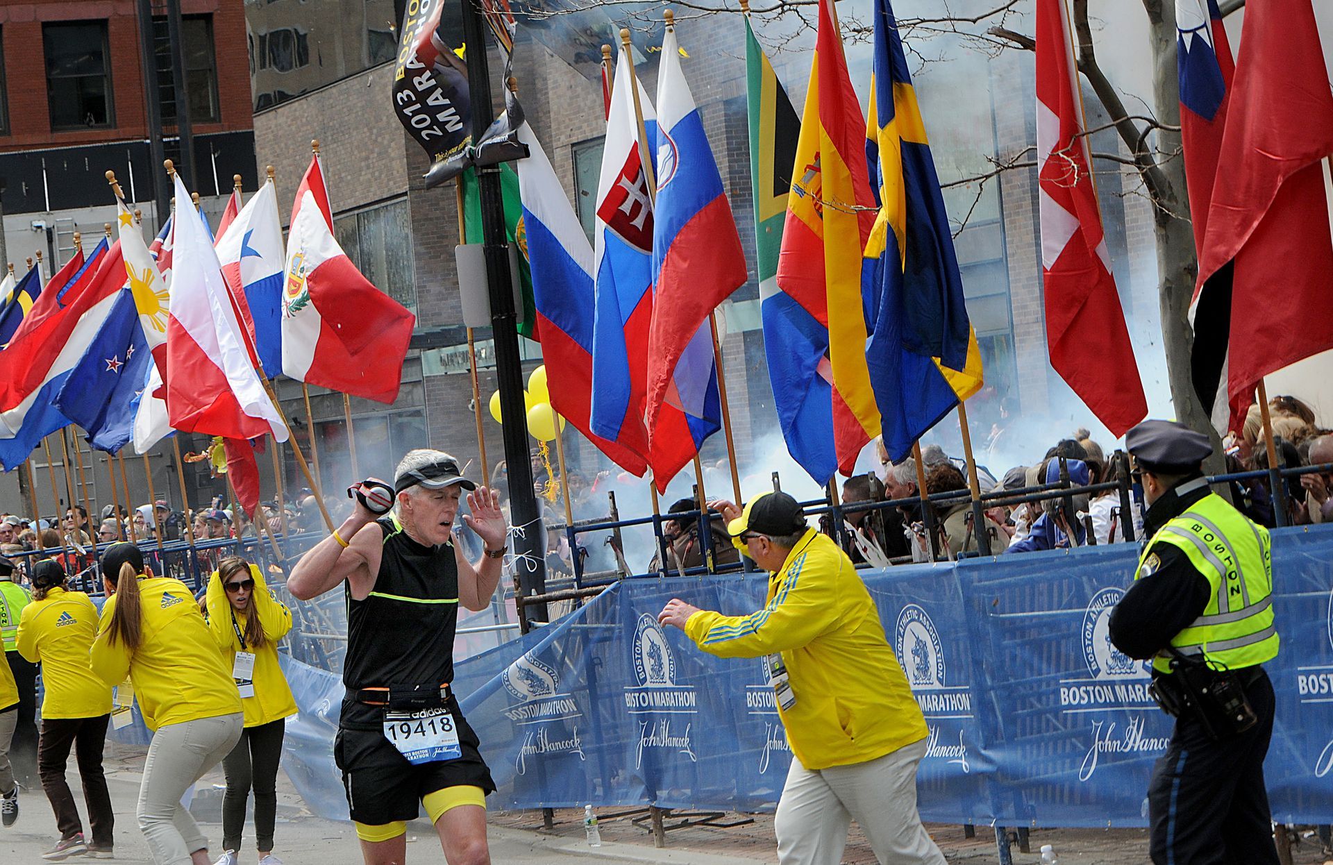 Runners, marathon officials and police react as a bomb explodes just a few yards from the finish line of the Boston Marathon on Monday, April 15, 2013.