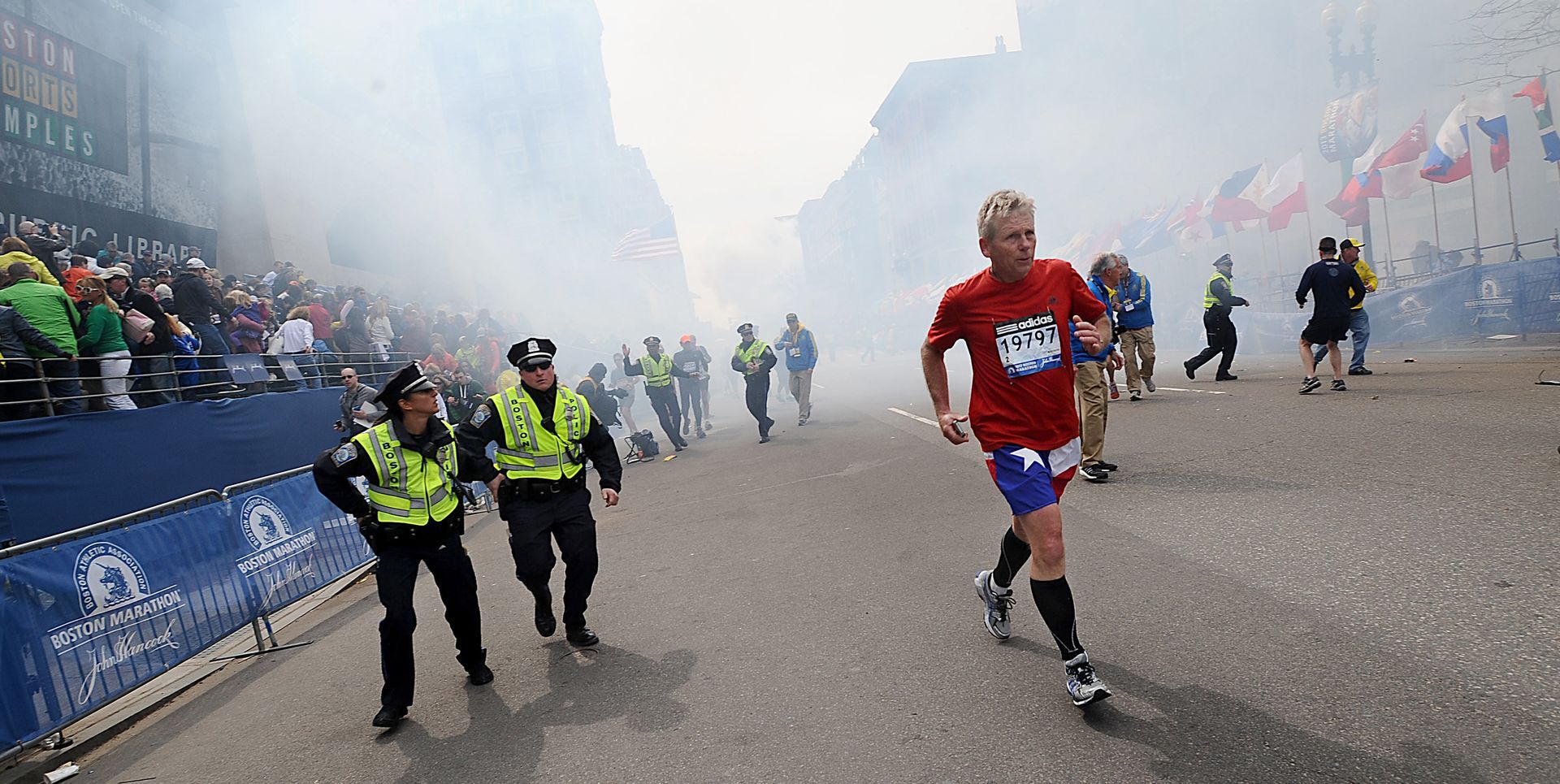 Runners, marathon officials and police react as a bomb explodes just a few yards from the finish line of the Boston Marathon on Monday, April 15, 2013.