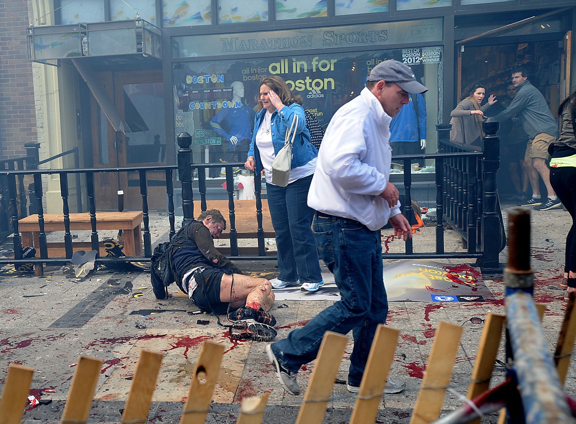 Injured spectators lie in the sidewalk as bystanders begin to react in front of Marathon Sports on Boylston Street in Boston shortly after a bombing yards away at the Boston Marathon finish line, April 15, 2013.