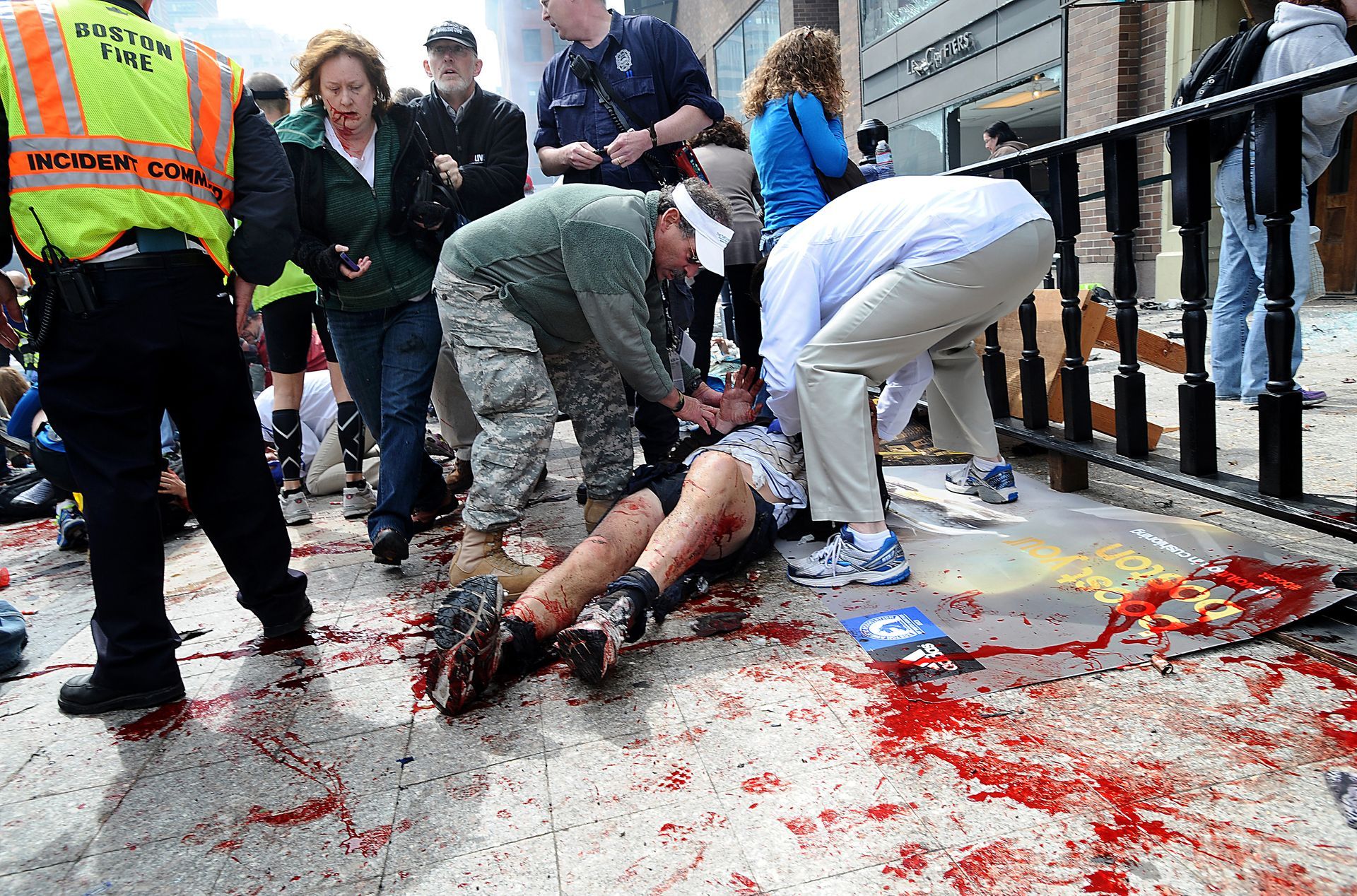 Good Samaratins tend to injured spectators on the sidewalk of Boylston Street in Boston after a bombing near the finish line of the Boston Marathon on Monday, April 15, 2013.