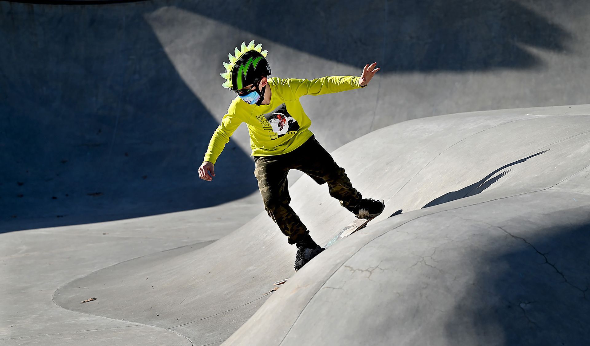 Riley Everett, 10, of Framingham and his colorful helmet and clothes cut through the shadows at the Farm Pond Skate Park in Framingham, March 23, 2021.