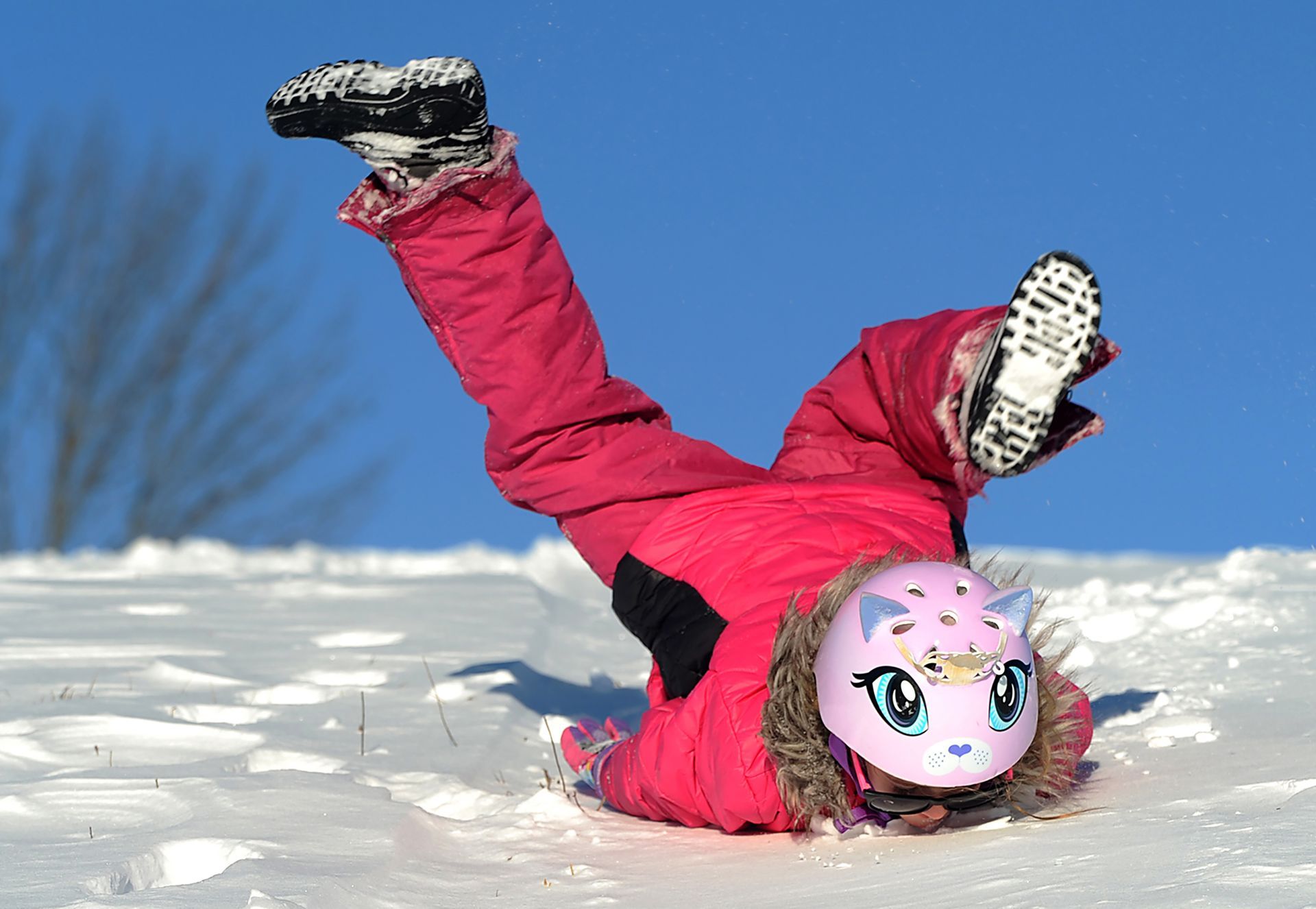Lilith McGrory, 7, of Medfield's face meets the snow as she rolls down a hill on the grounds of the Medfield State Hospital Friday, February 10 2017.