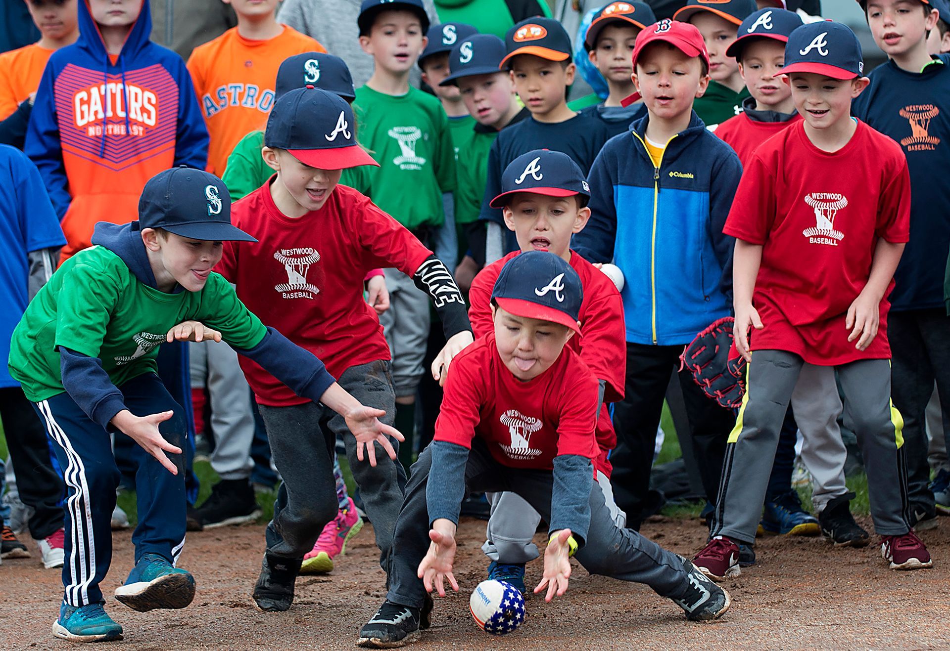 A group of Westwood Little Leaguers grab a ball hit by a stilt walker in a Yankees uniform during little league opening day festivities at Morrison Park in Westwood, Saturday, April 27, 2019.